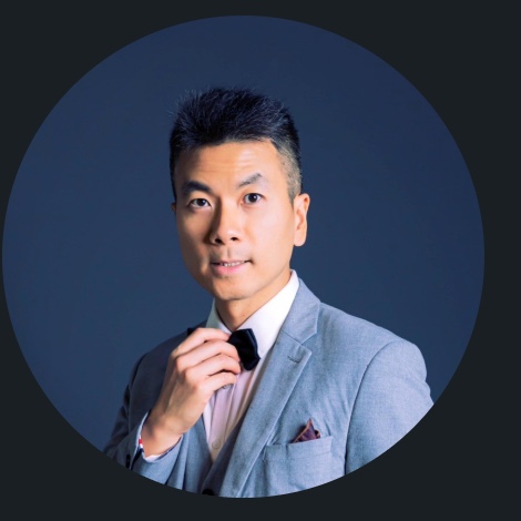 Tony Yang wearing a gray suit and adjusting his tie